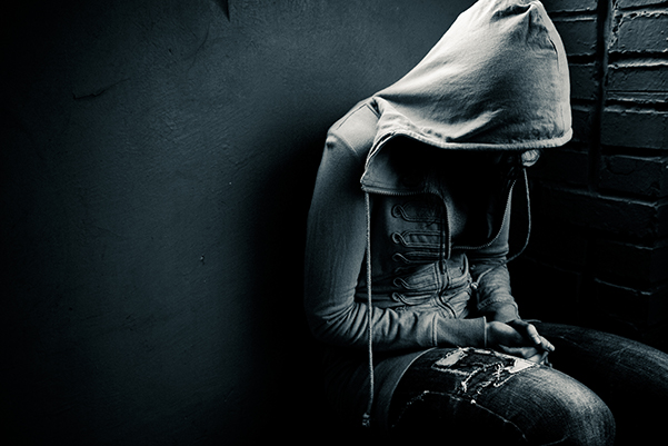 Depressed and potentially suicidal teenager or young person wearing a hoodie. Dark mood photo.